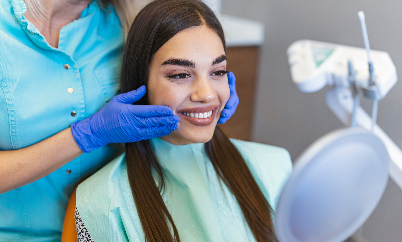 Woman admiring her smile in a mirror after cosmetic dentistry in Houston