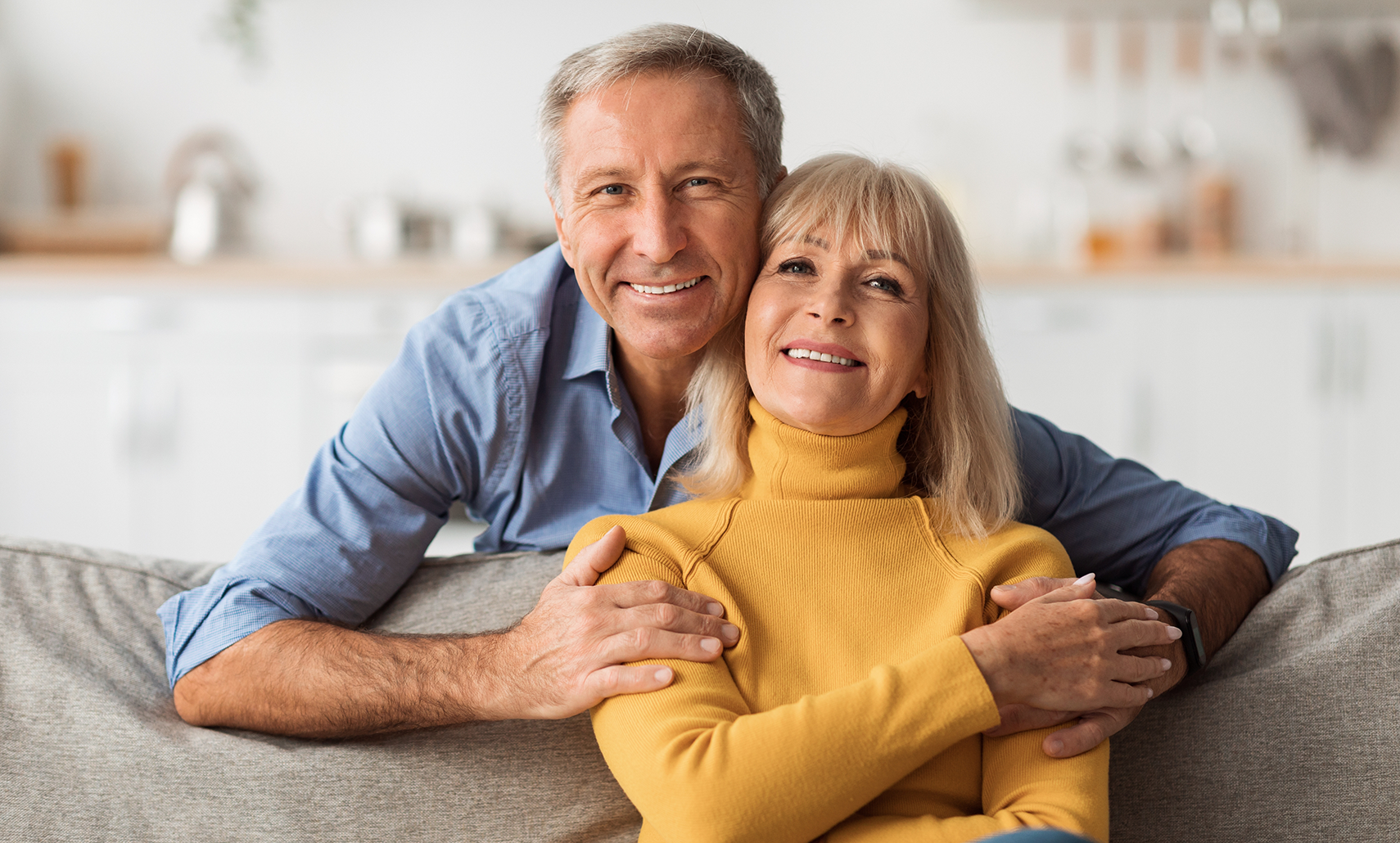 Older man and woman smiling on their couch